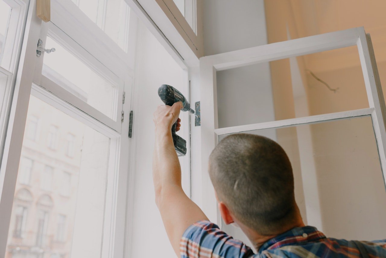 man removing screws from window fixture to replace the window frame