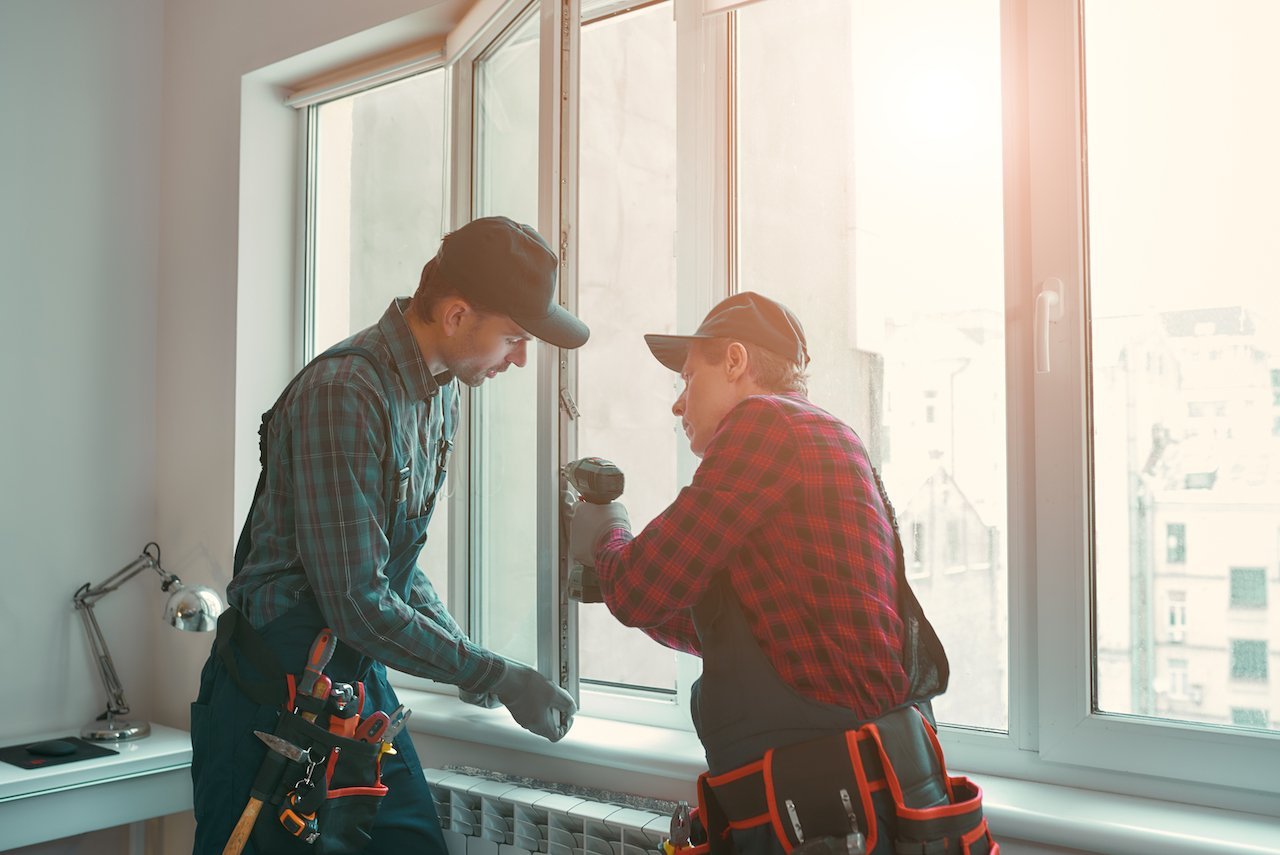 Two male certified window installers working on installing windows in a home